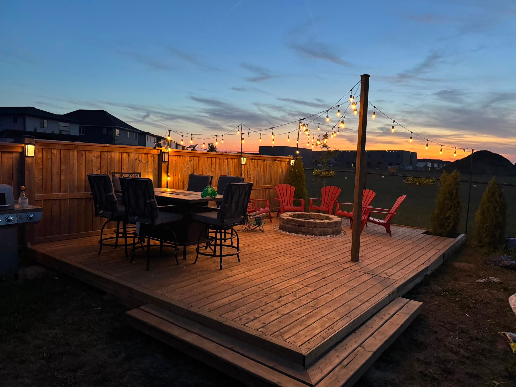 Custom deck with fire pit and string lights at sunset in London Ontario